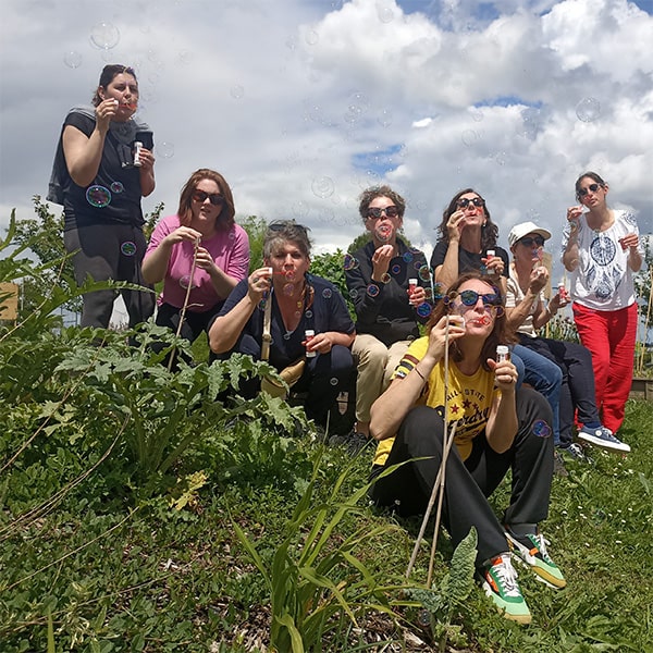 Photo de groupe d'une journée Sors de ta tanière. On voit un groupe de femme assises et debout dans l'herbe faisant des bulles de savon.